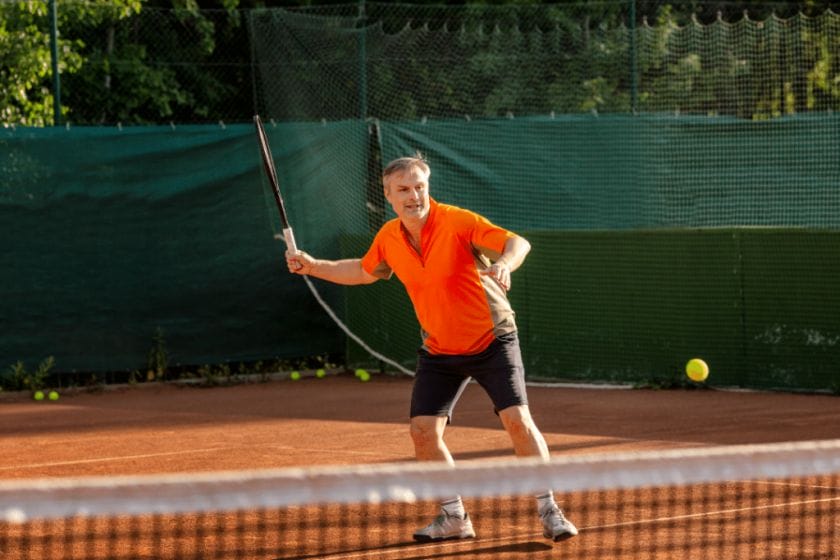 Elderly man playing singles tennis