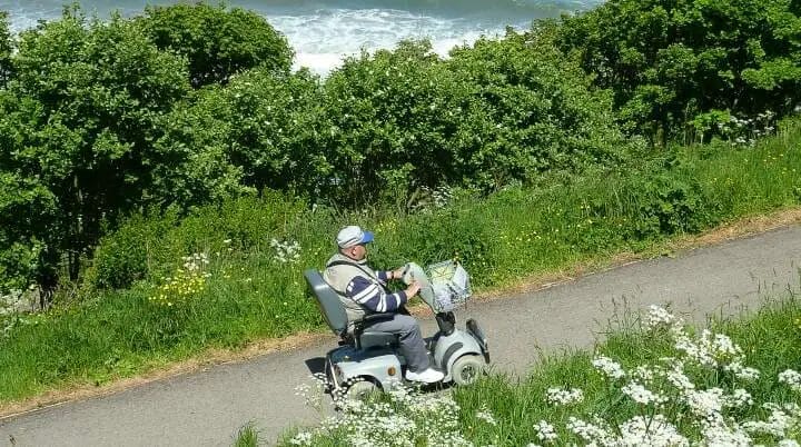 Man riding on mobility scooter up a steep hill.