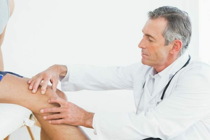 Doctor checking patients knee