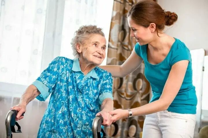 Senior woman assisted by her caregiver after hip replacement