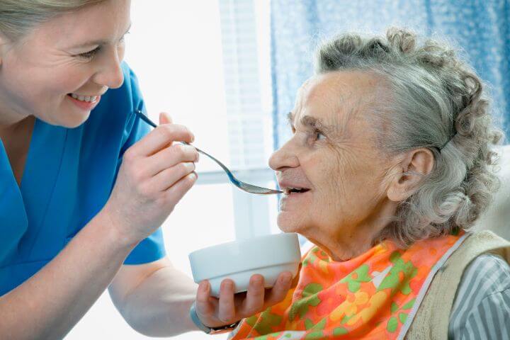caregiver feeding old woman