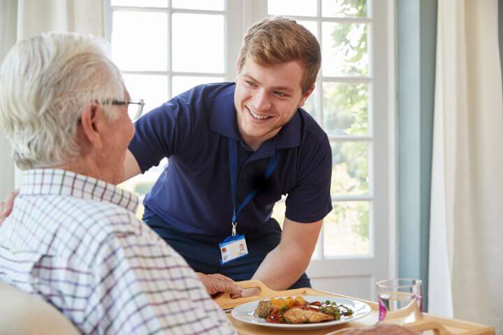 caregiver giving meal to senior man