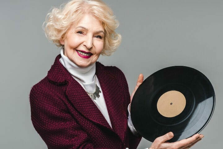 smiling old lady while holding a vinyl disc