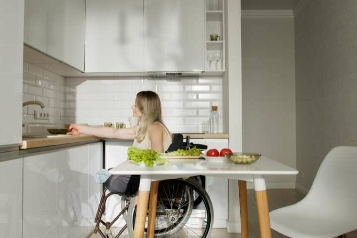 woman on wheelchair preparing meal